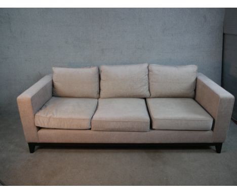 A contemporary three seater sofa, upholstered in light grey fabric, with angular arms, loose seat and back cushions, on an eb