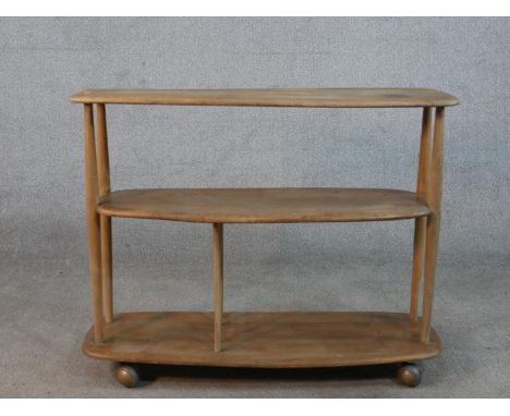 An Ercol blonde elm three tier trolley bookcase, model 361, raised on wheels with remains of label. H.70 W.89 D.31cm 