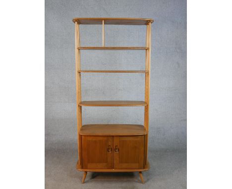 A 20th century Ercol blonde elm and beach Giraffe room divider, model 363, with adjustable shelves above two cupboard doors, 
