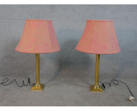 A pair of late 20th century brass table lamps in the form of Corinthian columns, on square step down bases with pink shades. 