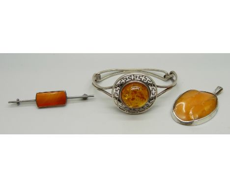 A butterscotch amber pendant, a silver and amber bangle and a brooch 