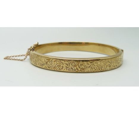 A 9ct yellow gold bangle with engraved front and safety chain, 9.9g 