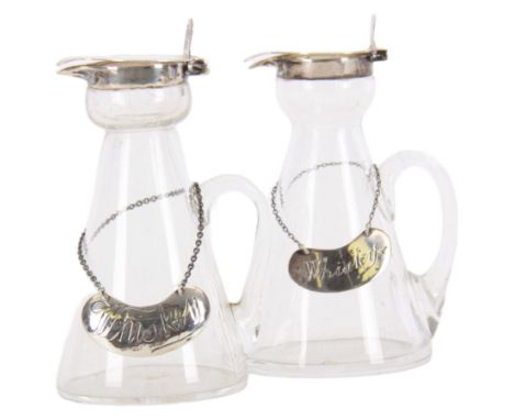 Two early 20th century silver mounted glass whiskey noggins, each of tapering cylindrical form with hinged flat covers and fl