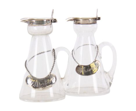 Two early 20th century silver mounted glass whiskey noggins, each of tapering cylindrical form with hinged flat covers and fl