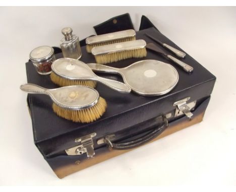 DRESSING CASE. A leather dressing case (distressed), with nine silver mounted brushes, jars &amp; tools.