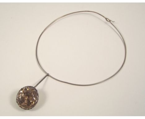 SILVER TORQUE.
A 1960's, 800 standard silver torque neck ring with a large smoky quartz drop in a modernist filigree setting.