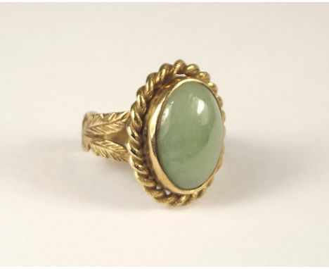 JADEITE RING. A pale green jade ring in ornate 9ct. gold setting. Size of stone 1.8 x 1.4cm. Size P.