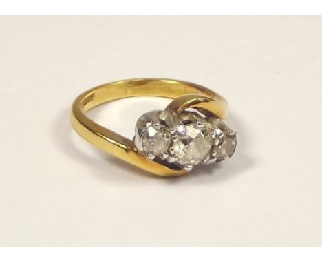 DIAMOND RING. An 18ct. gold, three stone cross-over diamond ring. Largest stone approx. 0.60ct. spread. Flanking stones each 