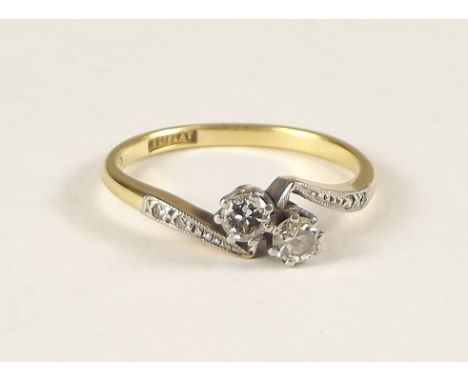 DIAMOND RING. An 18ct. gold &amp; platinum twin stone diamond crossover ring. Size K/L.