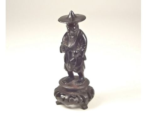 AMBER FIGURE. A carved red amber oriental figure of a fisherman set into a carved hardwood stand. Height 12cm. (lacks stick &