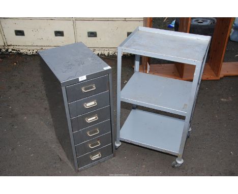 A metal filing cabinet and metal shelf on wheels.