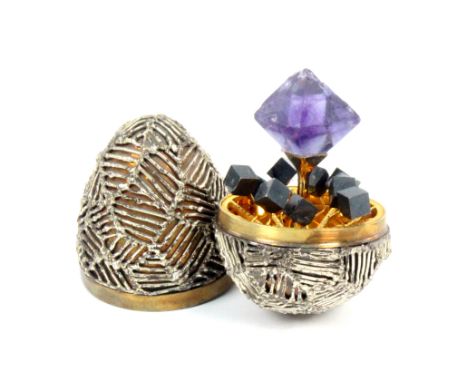 A Stuart Devlin silver and silver gilt surprise egg, the egg with lattice work overlay, the gilded interior with central amet