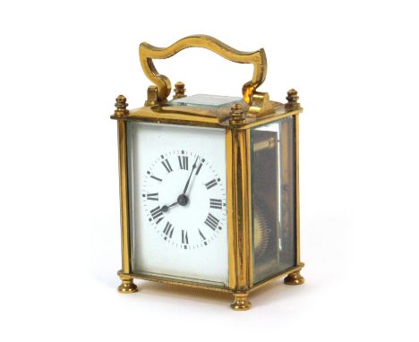An early 20th Century carriage style timepiece, enamel dial, brass and glass case, eight-day movement, one-foot lacking, 12cm