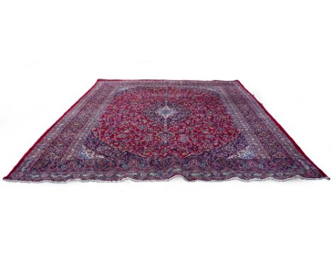 A MODERN RED GROUND ORIENTAL KASHAN STYLE SMALL CARPET with central blue ground motif and surrounded by floral designs within