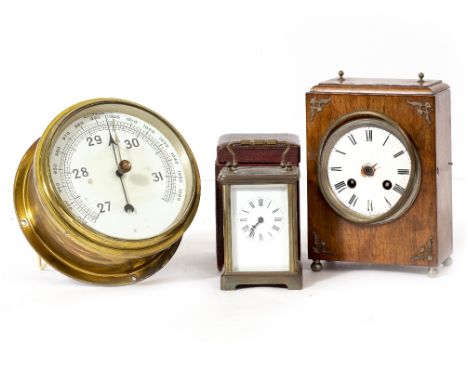 A BRASS CIRCULAR SHIPS BAROMETER measuring in millibars, 17cm diameter together with a carriage timepiece and a walnut cased 