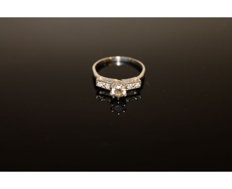 A diamond solitaire ring, a brilliant-cut diamond within a raised claw setting upon diamond set shoulders, to a plain shank, 
