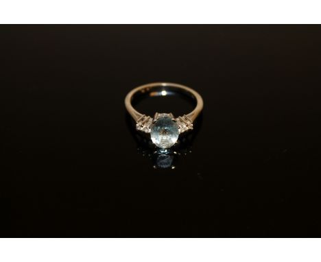 An 18ct white gold aquamarine and diamond ring, an oval-cut aquamarine within a claw setting, flanked by four brilliant-cut d