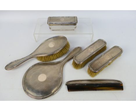 A George V silver mounted six piece dressing table set with engine turned decoration, comprising three brushes, comb, hand mi