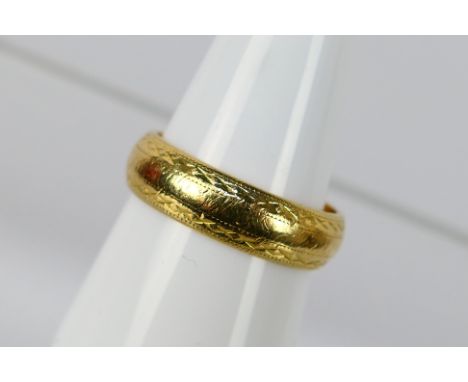 An 18ct yellow gold band ring with chased decoration, size R, approximately 7 grams. [W]