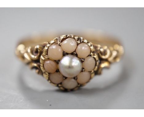 An early 20th century yellow metal, split coral and split pearl cluster set ring, size P, gross weight 2.5 grams.