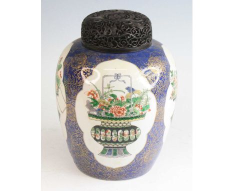 A Chinese famille verte porcelain jar, 19th century, having a profusely carved hardwood lid, enamel decorated with alternatin