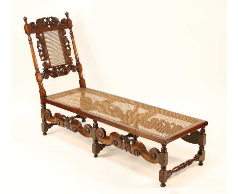 A Caroleon period and later joined fruitwood daybed, having split cane back and seat, Baroque influenced carved frieze (resto