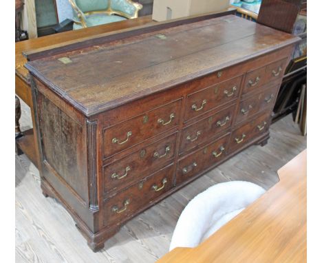 A Georgian oak mule chest, having fluted quarter columns, six dummy drawers above three drawers with loop brass handles and o