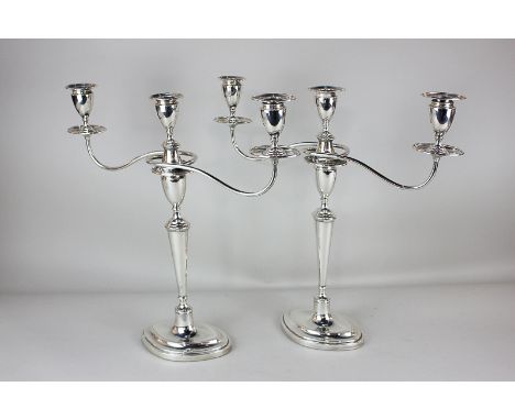 A pair of George V silver three-light candelabra with vase sconces, on detachable twin scroll branches, tapered stems and loa