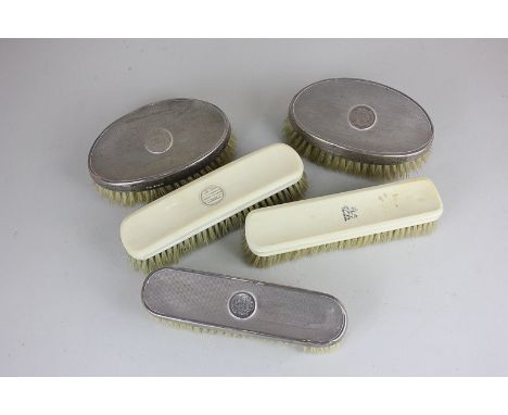 A pair of George V silver backed brushes, and another with engine turned decoration, with engraved coats of arms, and two oth