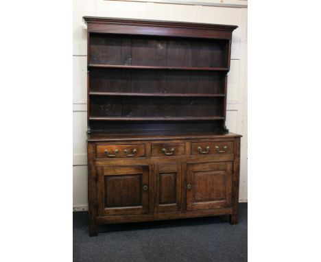 A George III oak dresser with later three shelf back, on base with three drawers, and two panelled cupboards with central pan