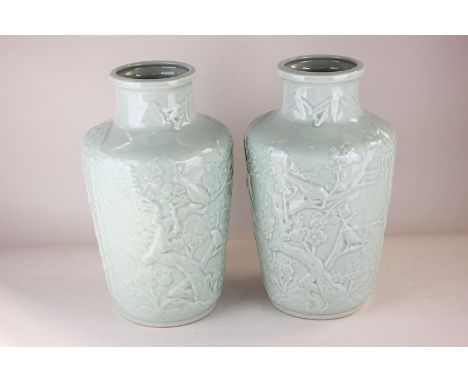 A pair of Chinese celadon vases cast in light relief with scenes of birds amidst blossom and bamboo, character marks to base,