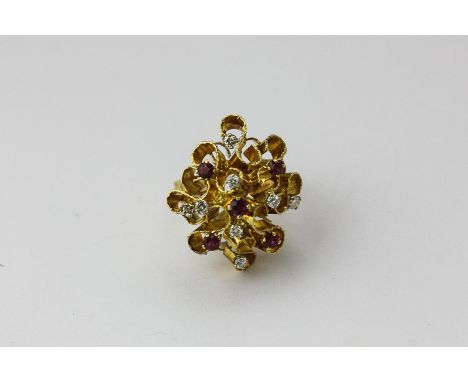 A ruby and diamond cluster ring, clear set with circular cut stones in a textured gold abstract style mount, 11.8g gross