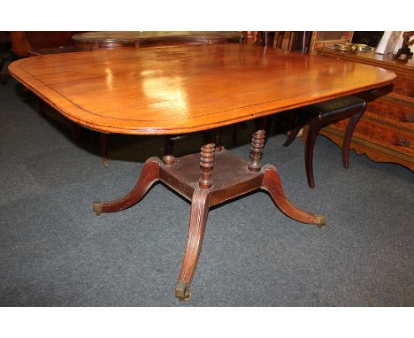 A Victorian mahogany dining table, with shaped rectangular top, turned supports and under shelf, on outswept legs, brass capp