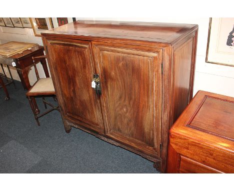 A Chinese hardwood cabinet, with twin panel doors and brass drop handles, enclosing two shelves, on shaped bracket legs, 108c
