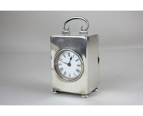 A silver cased travel clock with 4.5cm white enamel dial, in rectangular shaped case, with carry handle, hallmarks rubbed