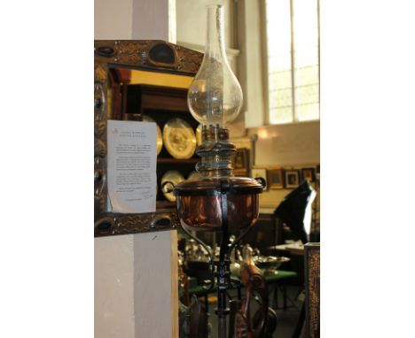 A Victorian copper oil lamp with funnel (lacks shade) on adjustable wrought iron stand 