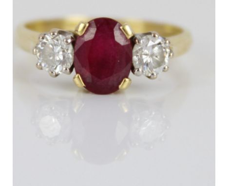 18ct yellow gold ruby and diamond ring, the central oval cut ruby flanked by two round cut diamonds, in claw settings, on tap