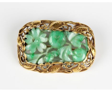 A gold and carved jade brooch, 1930s, the central jade carved as a flower, fruit and foliage, the mount decorated and pierced