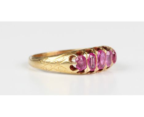 A gold and ruby five stone ring, mounted with a graduated row of oval cut rubies between decorated shoulders, unmarked, weigh