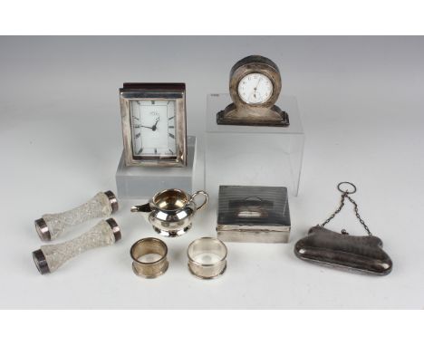 An Edwardian silver mounted bedside timepiece with circular enamelled dial and Arabic numerals, on a stepped rectangular base