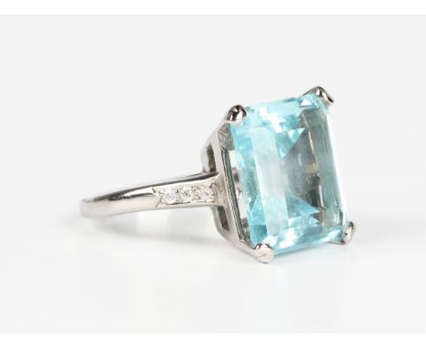 An aquamarine and diamond ring, claw set with the cut cornered rectangular step cut aquamarine between circular cut diamond s