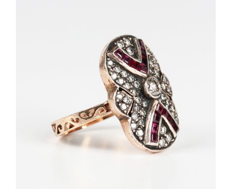 A gold and silver set, ruby and diamond panel shaped ring, the principal circular cut diamond between two 'V' shaped motifs s