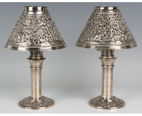 A pair of Cambodian silver candlesticks, each with cylindrical stem and foliate decorated band to circular base, marked 'T90%