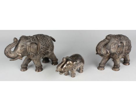 A pair of South-east Asian white metal models of elephants, each modelled with trunk raised, lengths 18.5cm, weight 914g, tog