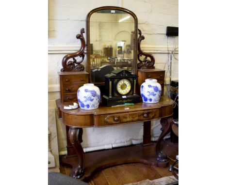 A mid Victorian mahogany dressing table, with arched plate on pierced scroll supports and six trinket drawers, the shaped top