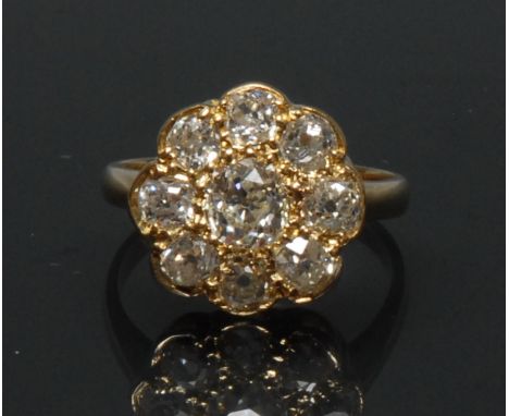 A diamond floral cluster ring, central round brilliant cut diamond approx 0,60ct, surrounded by a band of eight smaller confo