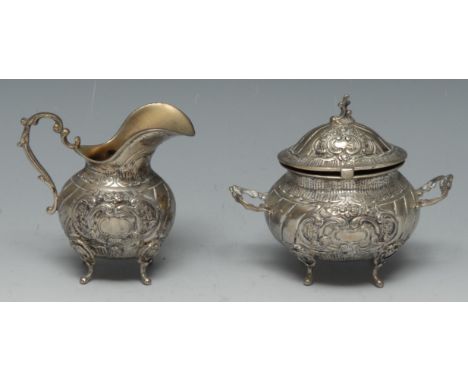 An early 20th century Swedish silver milk jug and sucrier spirally fluted and chased in the Rococo taste with leafy scrolls, 