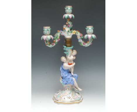 A Meissen figural four-light, three branch candlestick, the scroll arms encrusted with flowers and foliage, the column with c