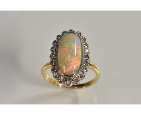 An opal and diamond cluster ring, central oval opal cabochon, measuring approx 14mm x 7mm, flashing vibrant orangey red, gree