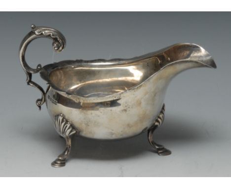 An Edwardian silver sauce boat, of George III design, shaped everted rim, acanthus capped flying scroll handle, hoof feet wit